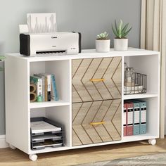 a white bookcase with two drawers and some books on the bottom shelf next to a printer