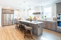 a kitchen with stainless steel appliances and wooden flooring, along with an island in the middle