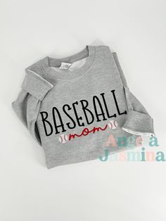 Elevate your game day look with our embroidered 'Basketball Mom, Soccer Mom or Baseball Mom' sweatshirt! Show your unwavering support for your favorite player with this cozy and stylish addition to your wardrobe. Crafted with meticulous attention to detail, each letter is expertly embroidered to ensure durability and longevity. Made from premium quality materials, this sweatshirt offers both comfort and style, making it perfect for cheering on your athlete from the stands or while running errand Sporty T-shirt With Embroidered Graphics For Game Day, Long Sleeve T-shirt For Baseball Game Day, Sporty Cotton T-shirt With Ribbed Cuffs, Sporty Winter T-shirt For College, Winter Cotton Sweatshirt With Baseball Collar, Sports Cotton Tops With Embroidered Logo, Varsity Style Tops For Game Day, Sporty Embroidered Graphics Tops For College, Sporty Tops With Embroidered Graphics For College