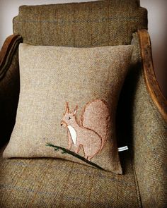 a brown chair with a pillow on top of it and a squirrel embroidered onto the back