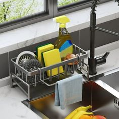 a kitchen sink filled with cleaning supplies next to a metal faucet and window