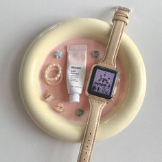 an apple watch sits on top of a plate with other items around it, including bracelets and rings