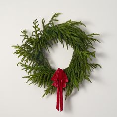 a christmas wreath hanging on the wall next to a red ribbon and a green twig