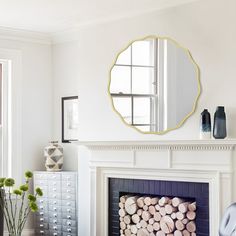 a living room filled with furniture and a fire place covered in logs next to a mirror