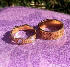 two gold rings sitting on top of a purple blanket