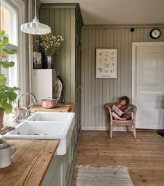 a little boy sitting in a chair next to a kitchen sink