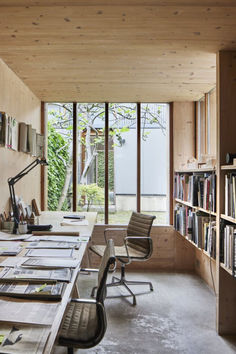 an office with lots of books on the shelves and desks in front of large windows