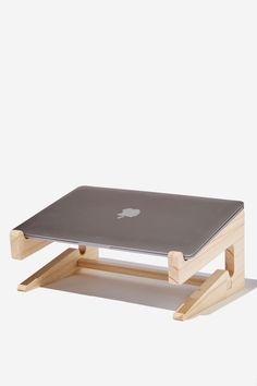 an apple laptop sitting on top of a wooden stand