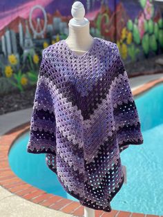 a purple crocheted shawl sitting on top of a white mannequin