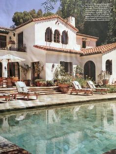 a house with a pool in front of it and some lawn chairs around the pool