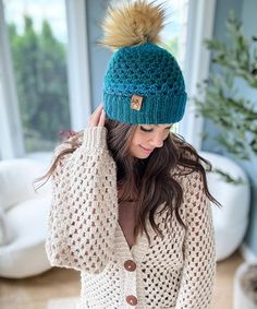 a woman wearing a knitted hat with a pom - pom on top