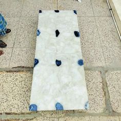 a man standing next to a white and blue piece of art on the ground in front of a building