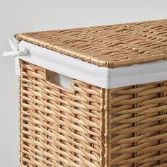 an empty wicker basket with white lining on the top and bottom, sitting against a wall