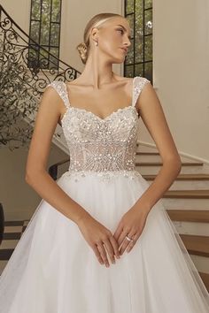 a woman in a white wedding dress standing next to stairs