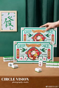 two people are playing with some kind of green cake board game on a wooden table