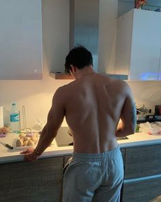 a shirtless man standing in front of a kitchen counter