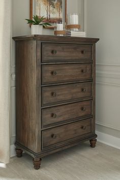 a wooden dresser sitting next to a window in a room with paintings on the wall