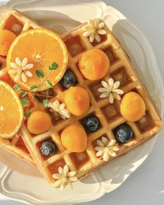 two waffles on a plate with orange slices and blueberries