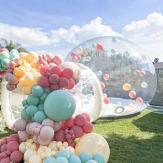 balloons are floating in the air next to a large bubble ball on some green grass