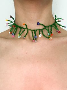 a woman wearing a green string necklace with multicolored beads on her neck and chest