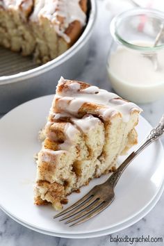 a slice of cinnamon roll cake on a plate with a fork and glass of milk