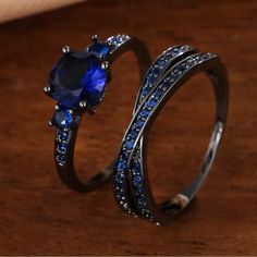 two rings with blue stones on them sitting on a table