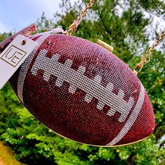 a close up of a football hanging from a chain with trees in the back ground