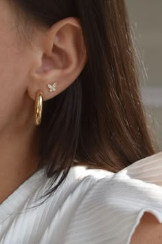 a close up of a woman's ear wearing gold earrings with small white flowers on them