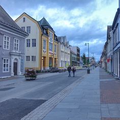 two people walking down the street in front of some buildings on either side of them