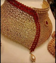 a gold and red beaded purse sitting on top of a white table next to jewelry