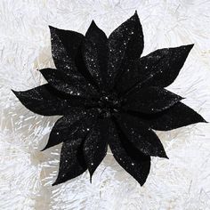 a large black flower sitting on top of a white surface with snow flakes in the background