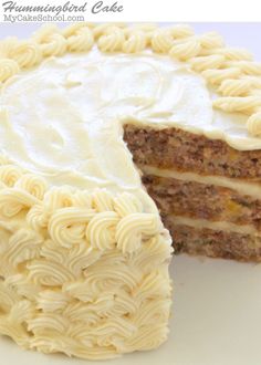 a piece of cake with white frosting is cut from the side and sits on a plate