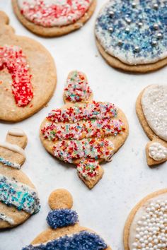 decorated cookies are displayed on a baking sheet with sprinkles and frosting