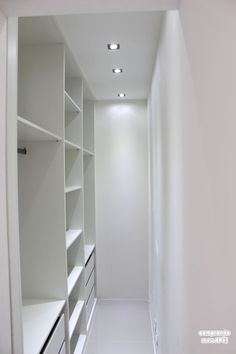 an empty walk in closet with white shelving and lights on the ceiling is shown