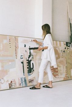 a woman standing in front of a large painting