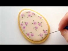 someone is decorating a decorated cookie with icing and pink flowers on the outside