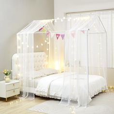 a bedroom with white furniture and lights on the walls, including a canopy bed that has sheer curtains over it