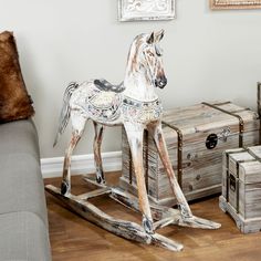 a wooden rocking horse sitting on top of a hard wood floor next to two trunks