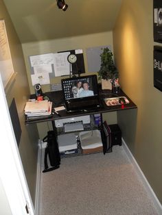 a desk with a computer and other items on it in an office space that is very small