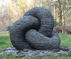 a sculpture made out of woven material sitting on top of a grass covered park area