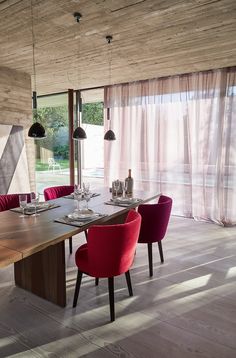 a dining room table with red chairs around it