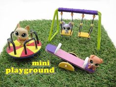 the miniature playground is set up in the grass with two cats on swings and a cat toy