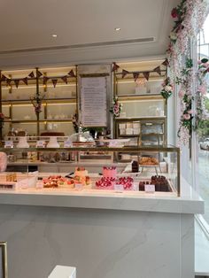 a display case filled with lots of different types of cakes and pastries in front of a window