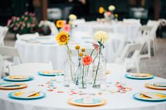 the table is set with flowers in vases, plates and napkins on it