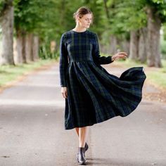 a woman is walking down the road in a dress