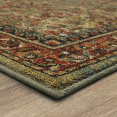 an area rug with wood flooring on top of it and a wooden table in the background