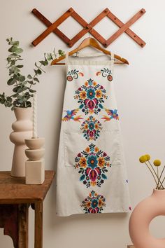 a white towel hanging on a clothes rack next to a vase with flowers in it