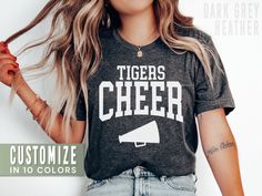 This personalized cheer shirt is the perfect tee to rep your school or cheerleader! Our Bella+Canvas tees have that light and vintage feel. ♥ 》 》HOW TO ORDER 《 《 * Select size + color from the drop down menus * Type your custom mascot in the personalization box. * Add to cart + place order ♥ * Your shirt is now in production & will be ready to ship in 1-3 days! 》 》SIZING 《 《 These are soft men's-cut shirts. Although these are unisex, I would NOT downsize. Check out the fit guide in the images. Varsity Tops For Cheerleading During Football Season, Team-colored Crew Neck T-shirt For Cheerleading, Cheerleading Fan Apparel Tops For Football Season, Customizable Casual T-shirt For Cheerleading, Cheerleading Graphic Print Team-colored Tops, Team-colored Tops With Graphic Print For Cheerleading, Cheerleading Graphic Print Fan Apparel Tops, Varsity Tops For Cheerleading, Football Season, Varsity Style Top For Cheerleading And Football Season