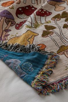 an image of a blanket with animals and mushrooms on it's edges, laying on a bed