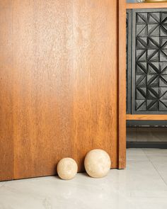 two balls sitting on the floor in front of a wooden door